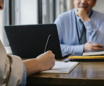 Crop anonymous female filling questionnaire when applying for job sitting in employer office